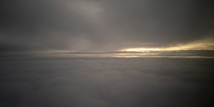 Bright sun rays light shining above dark cloudy sky. Sunset form airplane while flying