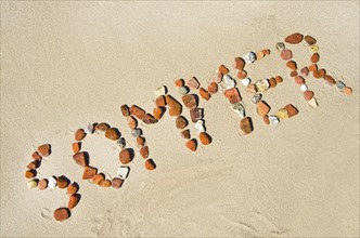 The word ?Sommer? (summer) made of rocks at the beach (in German)