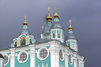 Golden domes of the Uspensky Cathedral on the background of a dark thundercloud. Smolensk, Russia,