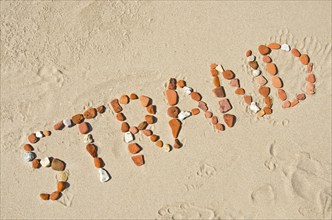 The word ?Strand? (beach) made of rocks at the beach (in German)