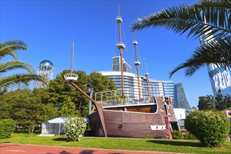 Batumi, Georgia, April 30, 2017: Park with palm trees, ship and modern houses near promenade