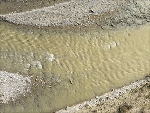 Muddy water flowing in the arda river near mignano val tolla in piacenza, italy, creating small