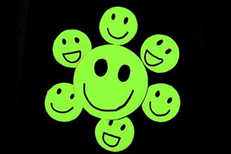 Cutout of green emoticons with smiley face on black background. Concept of well-being, good habits,