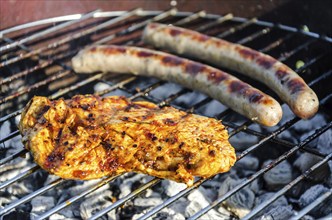 Chicken steak and sausages on a barbecue grill