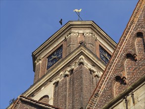 Detail of a church tower with weather vane and clock in sunlight, coesfeld, münsterland, germany