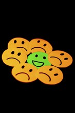 Paper cutouts of sad smileys surrounding a happy smiley. concept of positivism, social problems,