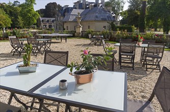 Tables decorated with flowers in the courtyard of the castle Grand Mello. France. Sunny day in