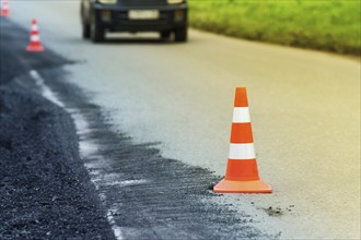 Warning traffic road cone set on asphalt street road during road repairing, asphalt pavement works