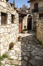 Stoned footpath crossing a traditional village. Stoned houses with wooden doors. Vintage