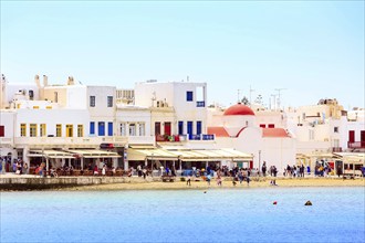 Mykonos, Greece, April 23, 2019: Famous island white houses, promenade, beach, view from the sea in