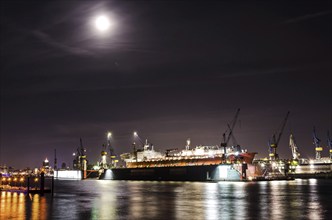 Night shot of dock with large container vessel on the Elbe river in Hamburg, Germany, Europe