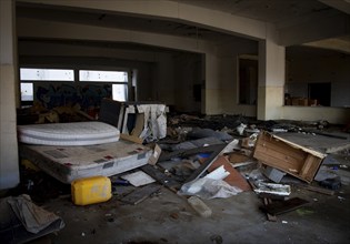 Interior of an old abandoned house kitchen with damaged furniture and a messy floor