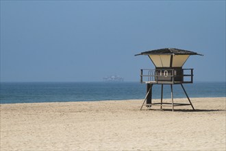 Oil rig near beach with lifeguard tower