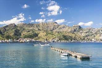 Wooden pier and some boats in beautiful bay with mountains in the background on the island Sicily