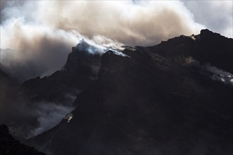 Gloomy atmosphere with smoke and steam on the summit of the volcano