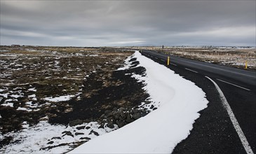 Rural empty straight road partly covered in snow in Reykjanes peninsula in Iceland