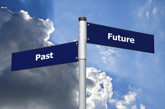 Street sign in front of cloudy sky representing crossroads between ?past? and ?future?