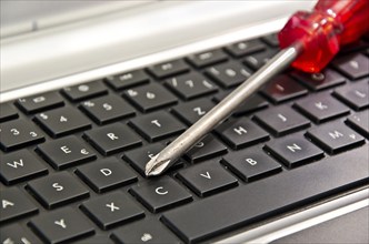 Screwdriver on computer keyboard symbolizing IT maintenance