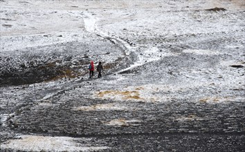 Unrecognized people trekking on a curved nature trail covered in snow in Iceland