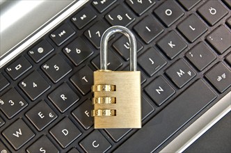 Padlock lying on computer keypad symbolizing data security