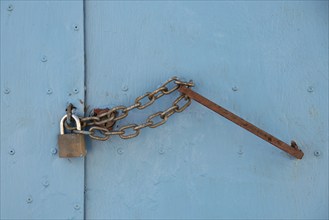 Blue closed metal door with locker iron chain for safety. Keep safe for robbery