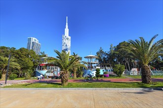 Batumi, Georgia, April 30, 2017: People walking in the park with palm trees near promenade