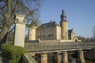 A castle with a bridge over a moat, flanked by two striking towers under a blue sky, Borken, North