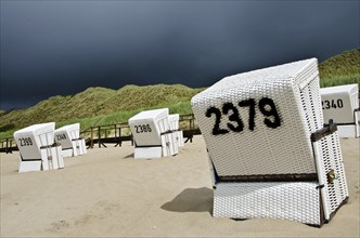 Empty beach chairs with dark clouds looming in the background