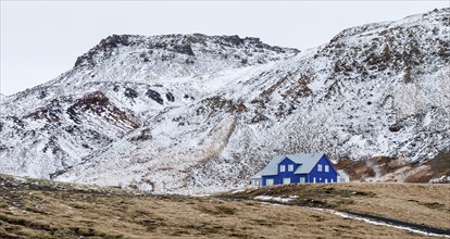 Icelandic landscape with blue chalet farm house in Reykjanes peninsula, Mountains covered in snow