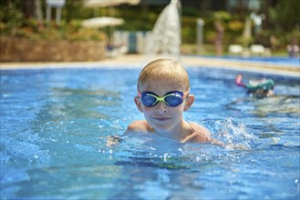 Young boy kid child eight years old splashing in swimming pool having fun leisure activity. Boy