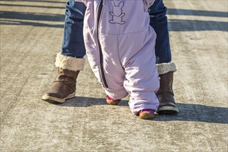 First steps of a toddler in winter garments