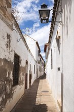 Old typical narrow street in the jewish quarter of Cordoba with old buildings with white walls