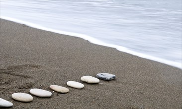 Smooth beach stones in a row and sea wave. Long exposure photograph