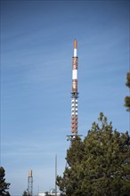 Communication tower on a building with 4G 5G antenna and satellite dish against blue sky. Mobile