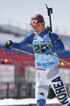 Sportsman biathlete Cheon Yunpil South Korea skiing on ski track distance biathlon arena. Junior