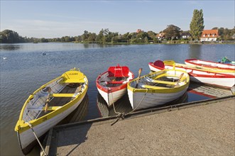 Colourful rowing boats on the Meare boating pond, Thorpeness, Suffolk, England, UK