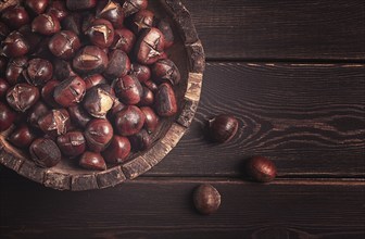 Roasted chestnuts, in a wooden plate, top view, homemade, no people