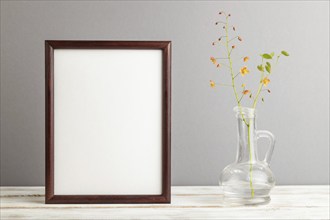 Wooden frame with orange barrenwort flowers in glass on gray pastel background. side view, copy