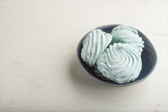 Blue colored homemade zephyr or marshmallow on white wooden background. side view, copy space