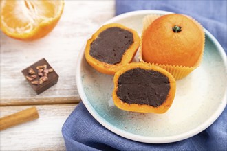 Truffle chocolate tangerine candies on a white wooden background and blue linen textile. Side view,