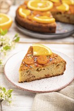 Orange cake and a cup of coffee on a white wooden background and linen textile. Side view, close