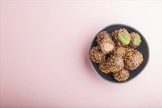 Chocolate caramel ball candies with almonds on a pastel pink background. top view, flat lay, copy