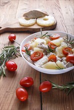 Chicken fillet salad with rosemary, pineapple and cherry tomatoes on brown wooden background. close