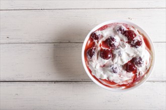 White plate with greek yogurt and strawberry jam on white wooden background. top view. copy space