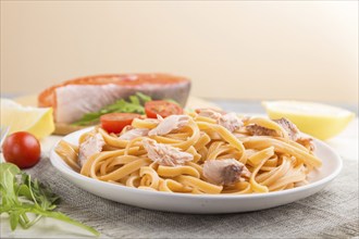 Semolina pasta with salmon and salmon steak on a white wooden background and linen textile. Side