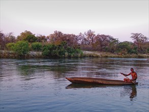 A Kavango fisherman pulls a net through a side arm of the Okavango River in the evening with his