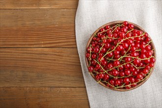 Fresh red currant in wooden bowl on wooden background. top view, flat lay, copy space