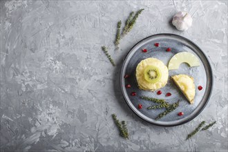 Pieces of baked pork with pineapple, cheese and kiwi on gray plate, side view, close up, top view,