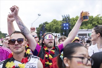 A fan celebrates with sunglasses, beer and feather boa in the fan zone at the Brandenburg Tor