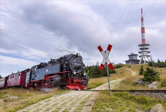 A steam locomotive with a train of the Harz narrow-gauge railway reaches the summit of the Brocken,